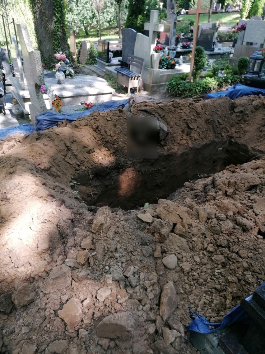Ludzkie szczątki (zapikslowane) leżące obok grobu.