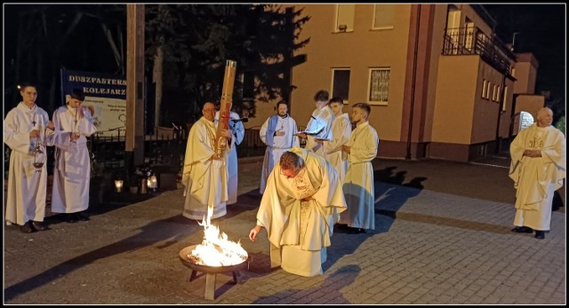Przed kościołem ksiądz błogosławi ogień, od którego zapala się paschał. Na świecy paschalnej kapłan kreśli krzyż i litery: Α (alfa) i Ω (omega)
