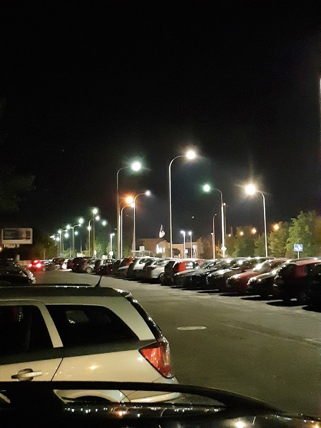 Podwójne oświetlenie przy ul. Pużaka, podczas gdy pobliski parking tonie w mroku.