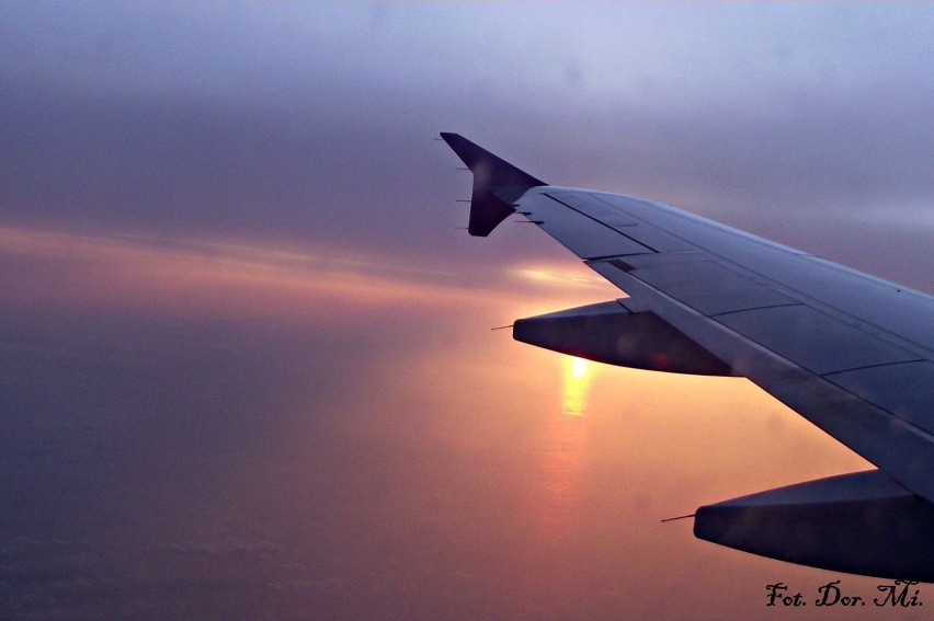 Z maleńkiego okienka samolotu, wschodzące słońce.