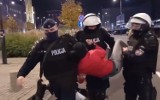 Dziewczyna nie chce się wylegitymować - policjanci podnoszą ją za nogi i ręce. Wśród nich łódzki funkcjonariusz FILM