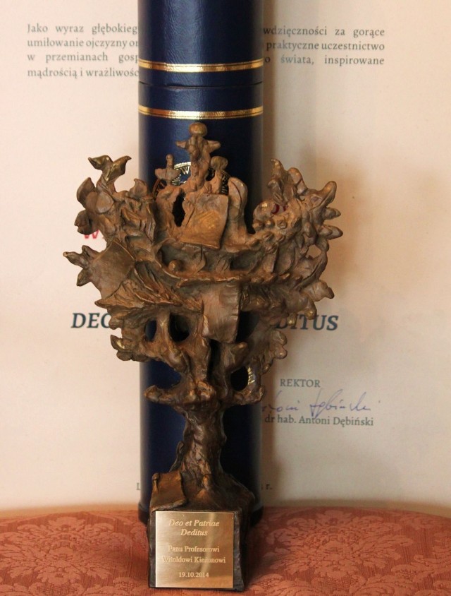 Statuetka na tle dyplomu przyznania tytułu honorowego Deo et Patrie deditus.