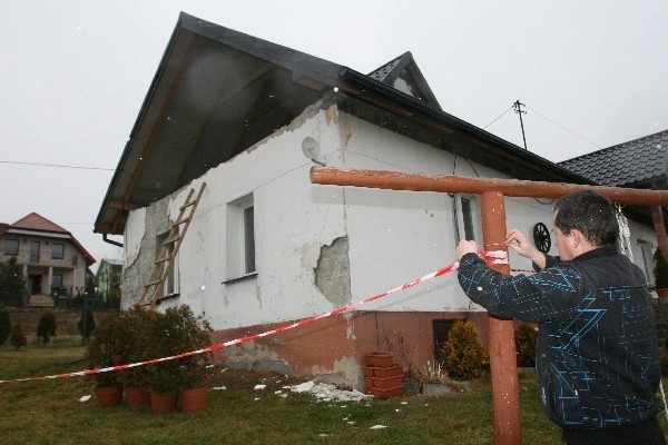 Łukasz Majerski z Biczyc Dolnych poprawia taśmę strażacką wokół uszkodzonego domu