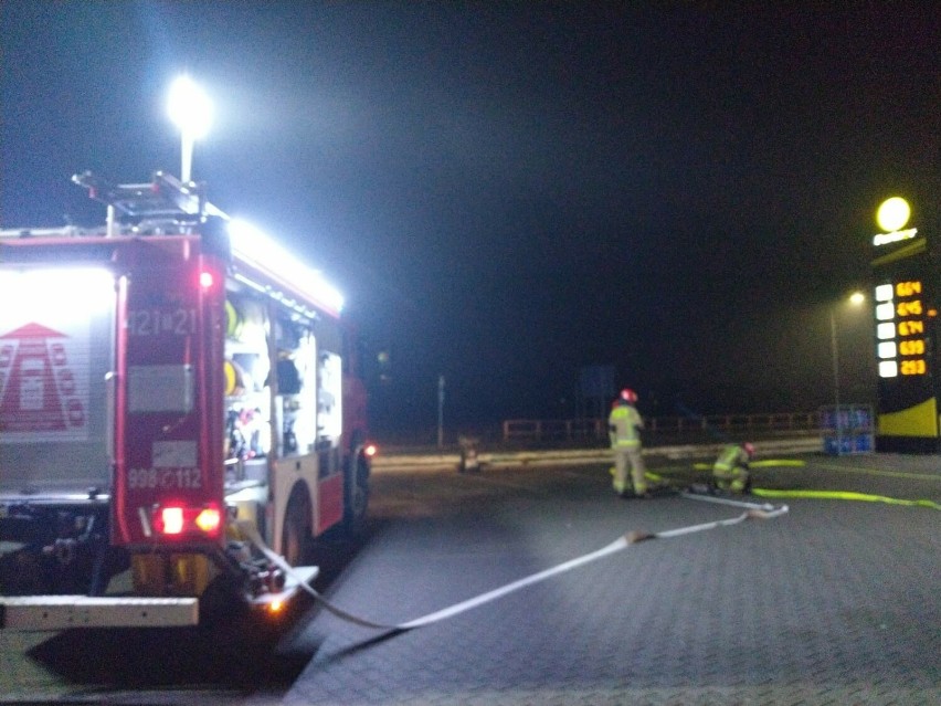 Wozy strażackie nocą na terenie stacji paliw w Kazimierzy Wielkiej. Podjeżdżają tak przez trzy dni