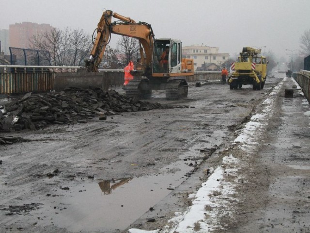 Piesi chodzący wiaduktem muszą chodzić między maszynami i stertami starego asfaltu.