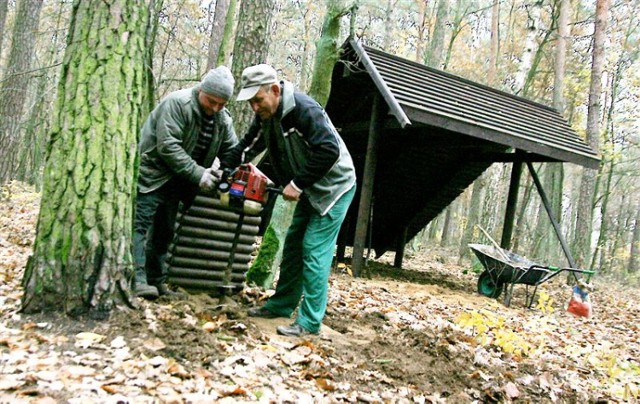 Łukasz Chwała i Sylwester Rogulski z Zakładu Usług Leśnych montują kosz przy jednej z altanek.