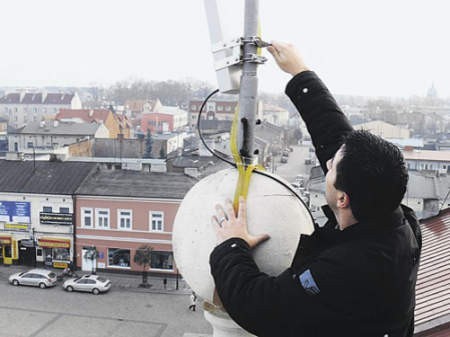Marcin Urbański montuje na wieży ratusza antenę do bezprzewodowego Internet