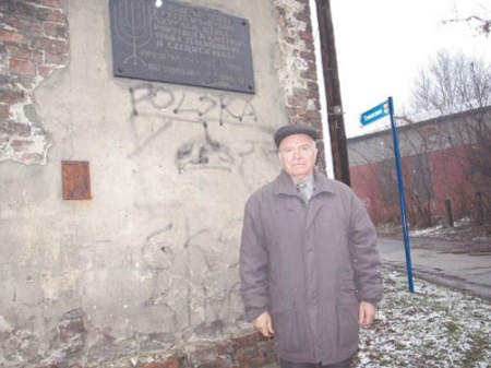 Łukasz Padoł pod tablicą na rozpadającej się kamienicy.