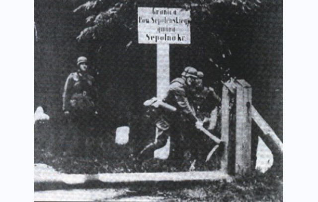 Wczesnym rankiem 1 września 1939 r. wojska niemieckie przekroczyły granice powiatu sępoleńskiego, rozpoczynając II wojnę światową. Fotografia przedstawia niszczenie szlabanu granicznego wykonana w kilka godzin po przejściu wojsk generała Guderiana, pod potrzeby propagandowej niemieckiej kroniki.