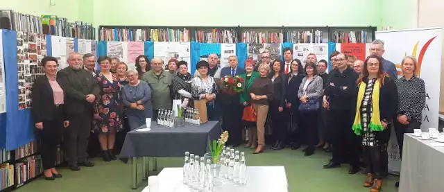 Uczestnicy otwarcia wystawy w wągrowieckiej bibliotece, prezentującej dorobek Stanisława Kaszyńskiego, widocznego na  fotografii w środku (z kwiatami)