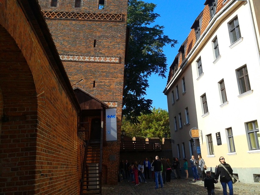 Turyści  w Toruniu sprawdzają  odchylenie krzywej wieży.