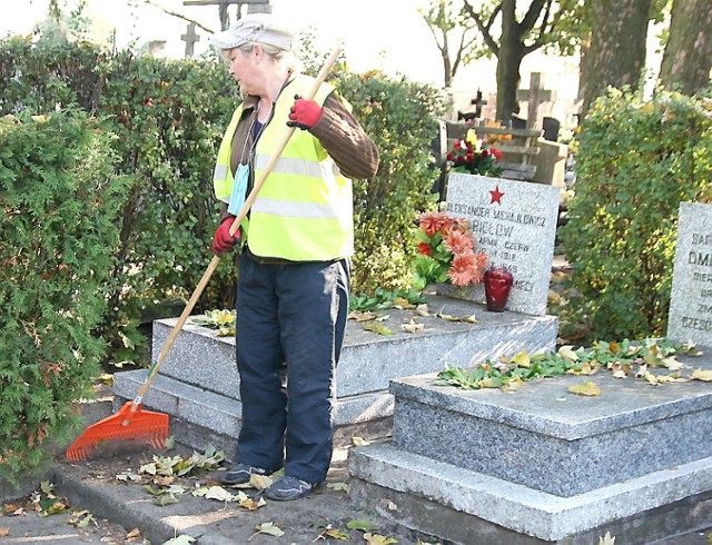 z Miejskiego Zakładu Usług Komunalnych sprząta wokół grobów żołnierzy radzieckich