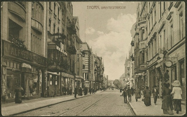 Tak prezentowała się ulica Szeroka na początku XX wieku. Po prawej stronie widać szyld i reklamę zakładu zegarmistrzowskiego Reinholda Schefflera, który w 1887 roku miał zbudować pierwszy w Toruniu zegar elektryczny.