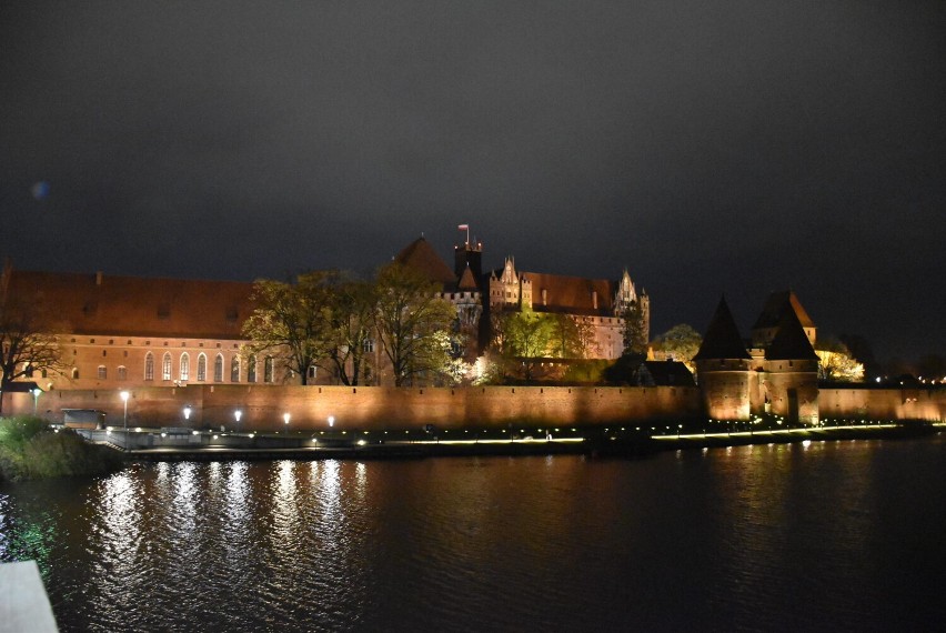 Zamek w Malborku i bulwar nad Nogatem wieczorową porą. Oświetlenie dodaje uroku reprezentacyjnym miejscom