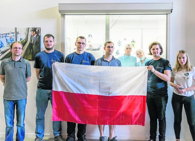 Na pierwszym zdjęciu członkowie zespołu PW-SAT 2 po udanej integracji satelity z oprzyrządowaniem. Michał Gumiela (po prawej) trzyma polską flagę.