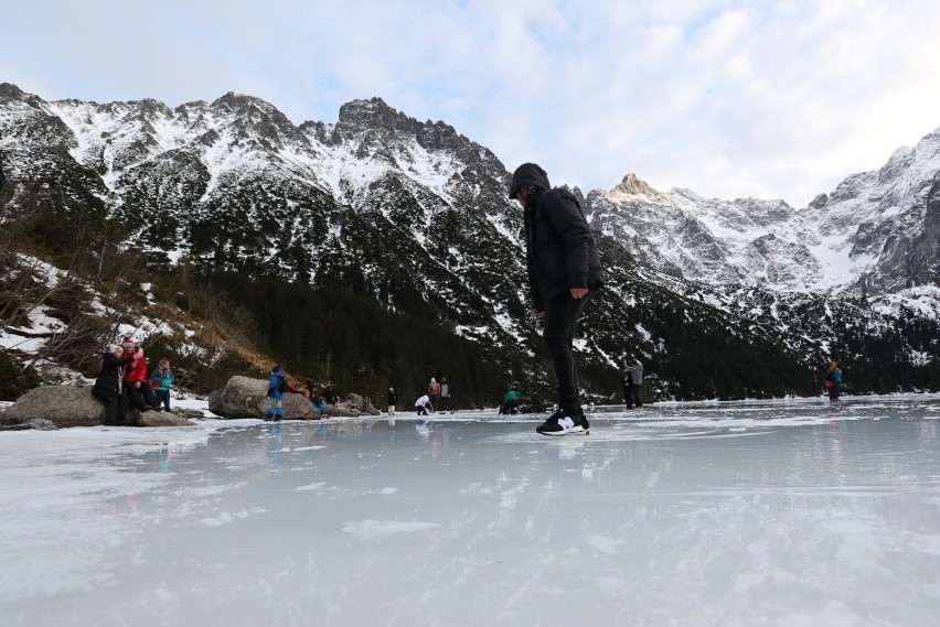 Turyści na tafli lodu na jeziorze Morskie Oko w Tatrach.