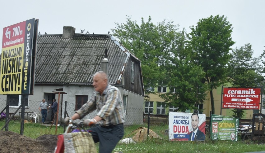 Andrzej Duda wśród reklam, tuż za rowerzystą