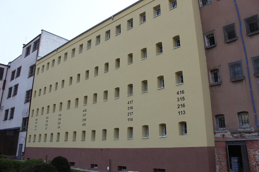 Front wyremontowanego pawilonu mieszkalnego. Elewacja budynku jest żółta, widać cztery rzędy okien. Na elewacji widoczne numery cel naniesione farbą koloru czarnego