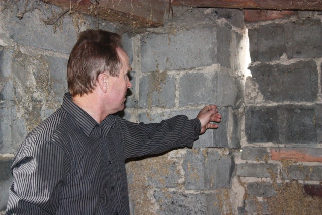 Kazimierz Merta pokazuje pęknięcia na ścianach budynku