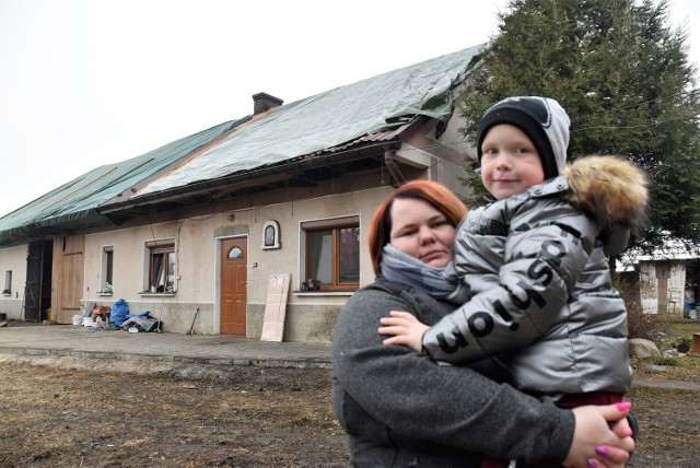 Pani Monika z najmłodszym z trójki synów - Kacprem przed uszkodzonym przez pożar budynkiem, w którym do niedawna mieszkali