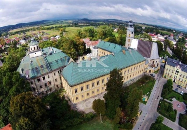 Opis nieruchomości


Do sprzedania zespół zamkowo-pałacowy w Międzylesiu, który zajął wysokie 12 miejsce w ogólnopolskim rankingu hoteli zamkowych . Międzylesie to miejscowość położona na ziemi Kłodzkiej, w województwie dolnośląskim, 6km od granicy polsko-czeskiej, zlokalizowanej przy międzynarodowej linii kolejowej Wrocław-Praga oraz drogi krajowej nr 33. Pierwsze wzmianki dotyczące budowy Zamku sięgają XIV w. , przy czym zasadniczą budowę zespołu datuje się na koniec XVI w. - XVII w. Obiekt wpisany do rejestru zabytków pod numerem 468 jako dobro kultury. Kompleks usytuowany jest przy samym rynku miejskim, a w jego skład wchodzi renesansowy zamek z dziedzińcem i wieżą, pałac barokowy, którego korpus zorientowany na linii północ-południe zamyka przestrzeń runku oraz skrzydło boczne. Całość wraz z murem wygradza przestrzeń wewnątrz tworząc dziedziniec pałacowy. W skład kompleksu wchodzi również zabudowa administracyjno-hotelowo-socjalna, powstała współcześnie. Całość otacza park ze stawem i położona jest na działce o powierzchni 1,78ha, a łączna powierzchnia użytkowa zabudowy przekracza 9 000m2. W latach 2008-2009 przeprowadzono rewitalizację północnego skrzydła barokowego, które zostało zaadaptowane na restaurację połączoną z salami myśliwskimi, sale konferencyjne i pokoje hotelowe. Obecnie mieści się tu hotel oferujący 56 miejsc apartamentowych i 14 turystycznych. Ponadto funkcjonuje tu również galeria sztuki przy współpracy z Muzeum Ziemi Kłodzkiej, kino plenerowe, gra Escape the Castle oraz odbywa się zwiedzanie nocne i dzienne, a także wesela i inne uroczystości. Funkcjonująca dziś część wykorzystuje około 25% potencjału całego obiektu. Zostały rozpoczęte stale postępujące prace odbudowy pozostałych dwóch skrzydeł - Zamek posiada uzgodniony z konserwatorem zabytków i zatwierdzony przez odpowiednie organy projekt budowlany rewitalizacji i adaptacji obiektu na centrum hotelowo-konferencyjne z reprezentacyjną salą balową, klubem nocnym oraz częścią rekreacyjno-wypoczynkową ze SPA i basenem ulokowanym pod zabytkowym dziedzińcem Zamku i w jego lochach. Obecnie wyremontowano m.in. sale balową z krużgankiem, sień przejazdową oraz elewację frontową drugiego skrzydła Zamku. Prace trwają bez kompromisu zniszczenia historycznej substancji architektonicznej - forma obiektu uwarunkowana została przeprowadzonymi badaniami historycznymi, a wszystkie elementy zabytkowe zostały w pełni zachowane i wykorzystane. Zamek to jeden z najważniejszych zabytków Ziemi Kłodzkiej. Nieruchomość posiada ogromny, już odkryty i wyzwolony potencjał rozwojowy. Zamek jest w programie Dolnośląskiej Organizacji Turystycznej: Europejski Szlak Zamków i Pałaców, jest członkiem Stowarzyszenia „Turystyczna Trzynastka”, do której należą takie obiekty jak Zamek Książ, Kopalnia Złota w Złotym Stoku czy wrocławskie ZOO, a także członkiem Fundacji Ochrony Dziedzictwa Kulturowego Hrabstwa Kłodzkiego oraz Polsko-Czeskiego Szlaku Turystycznego. Lokalizacja kompleksu to także doskonała baza wypadowa do wielu atrakcji dla osób aktywnie spędzających czas, uprawiających wspinaczkę skałkową, narciarstwo, kolarstwo czy jazdę konną. W bliskiej odległości znajdują się także liczne zabytki architektury takie jak Forteca w Srebrnej Górze, Sanktuarium w Wambierzycach, Podziemne Miasto Głuszyca - Kompleks Osówka, Sztolnie Walimskie w Górach Sowich. Kotlina Kłodzka oferuje również piękne tereny do pieszych wędrówek. Dla zainteresowanych inwestorów dysponujemy materiałami ukazującymi możliwe fazy rozwoju, analizy opłacalności inwestycji oraz specyfikacje techniczne zatwierdzonych projektów dalszej rewitalizacji. Więcej informacji i prezentacji, a także materiałów w języku angielskim na stronie internetowej Agencji Nieruchomości "KRUPIŃSKI".

CENA: 1 990 000,00 EURO. Podana kwota jest ceną netto liczoną po kursie z dnia 10.03.2016. Do ceny należy doliczyć 23% podatku VAT.

Według informacji właściciela bardziej opłacalnym wariantem dla inwestora jest zakup całej spółki - podatek VAT nie wystąpi.

Pośrednik odpowiedzialny za ofertę Henryk Krupiński licencja nr 3189.

Dane zamieszczone są na podstawie informacji dostarczonych przez właściciela.