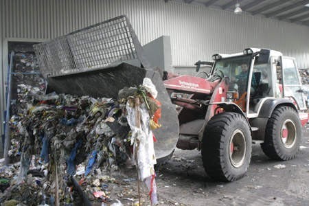 Zakład przetwarzania śmieci w Dąbrowie Górniczej. Krzysztof Adamowski ładuje odpady na taśmę transportową.