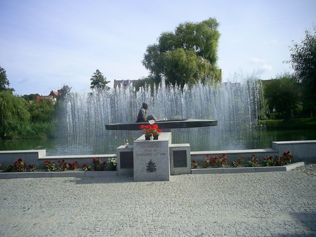 Pomnik Karola Wojtyły - papieża Jana Pawła II w Zbąszyniu; w głębi rzeka Obra.
