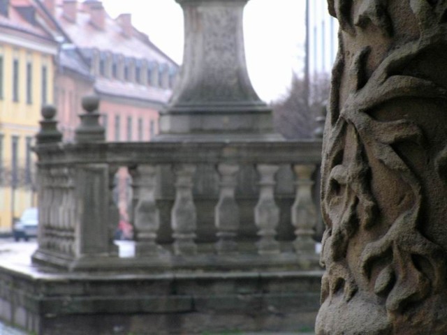 Ornamenty w portalu Katedry św. Jana Chrzciciela oraz pomnik przed wejściem do niej.  W tle ulica prowadząca do Mostu Tumskiego. Fot. Kamil Drejer