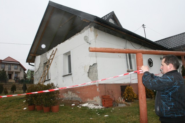 Łukasz Majerski z Biczyc Dolnych poprawia taśmę strażacką wokół uszkodzonego domu