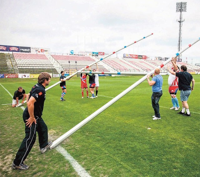 Na stadionie Widzewa trenerzy i zawodnicy Budowlanych ustawiają bramkę do rugby.