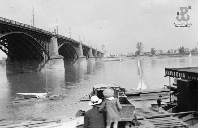 Fotografia z okresu okupacji niemieckiej. Warszawa. Kobieta z dzieckiem na brzegu Wisły przy ulicy Wioślarskiej. Ujęcie w kierunku wschodnim. Po lewej most Poniatowskiego, na wprost zabudowania na Saskiej Kępie.