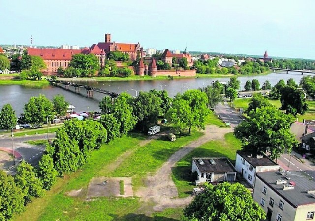 W głębi zamek, a na pierwszym planie u dołu zdjęcia jedna z dwóch działek w Kałdowie, które miasto chce sprzedać w jednym przetargu.