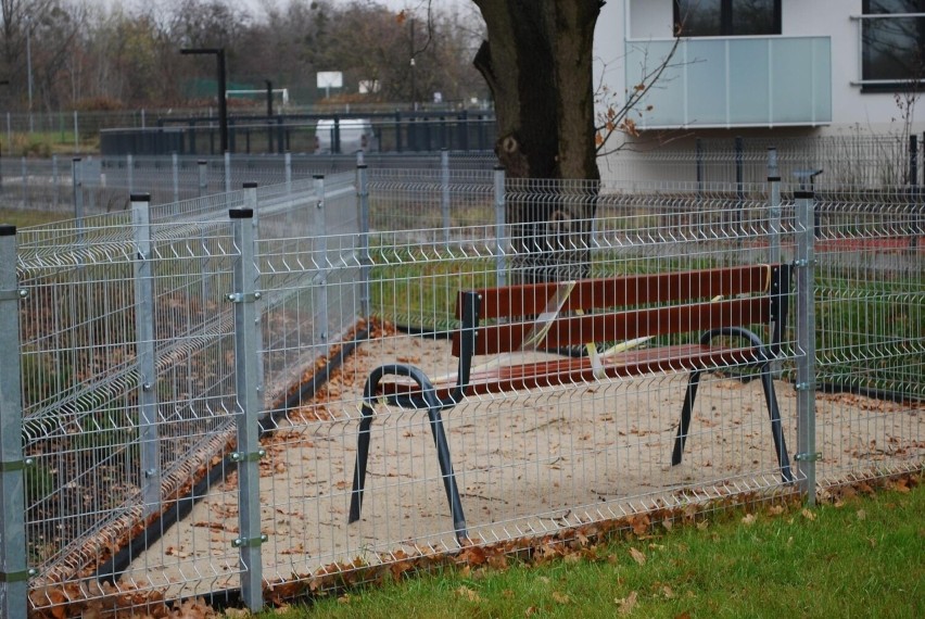 Ławka ogrodzona na niewielkiej, trójkątnej przestrzeni,...