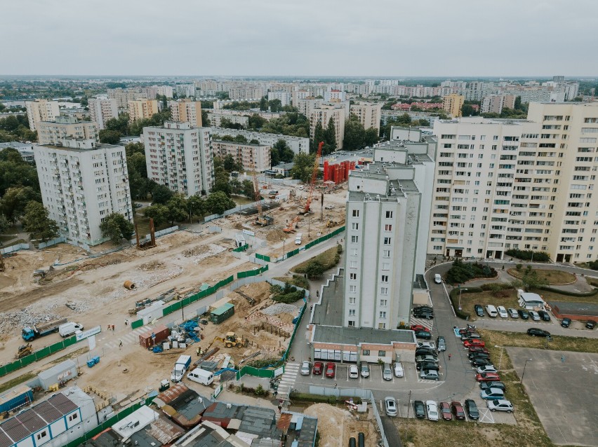 Widok z lotu ptaka na osiedle, otaczające budowę budynki.