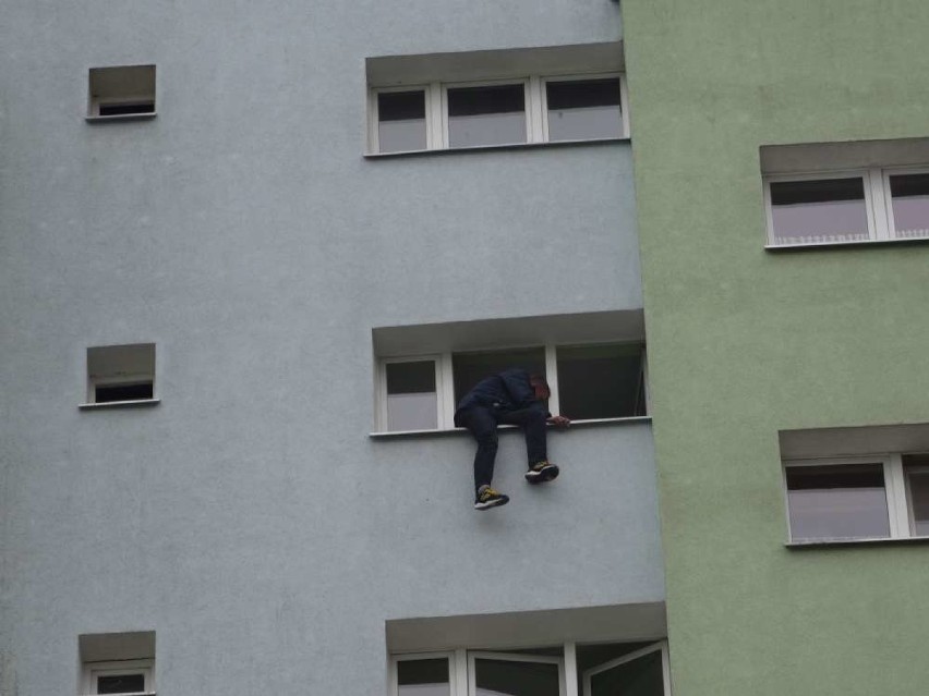 Mężczyzna na parapecie okna na wieżowcu w Pile