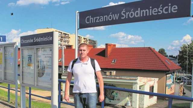 Dariusz Bartosiewicz na stacji Chrzanów Śródmieście. Tuż za nim stoi stary budynek dworca