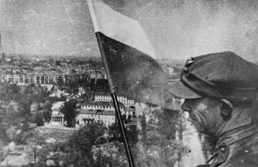 Żołnierz Wojska Polskiego z biało-czerwoną flagą na szczycie...