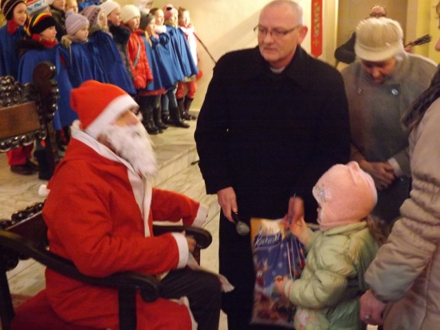 Św. Mikołaj przy pomocy członków i opiekuna stowarzyszenia wręcza paczki dzieciom