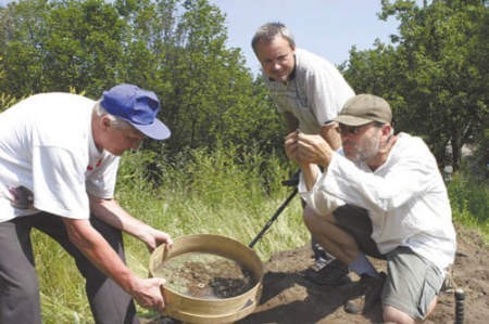 Jerzy Pelan, Krzysztof Kopeć i Leszek Krudysz na jednym ze stanowisk badawczych oglądają znalezione skarby.