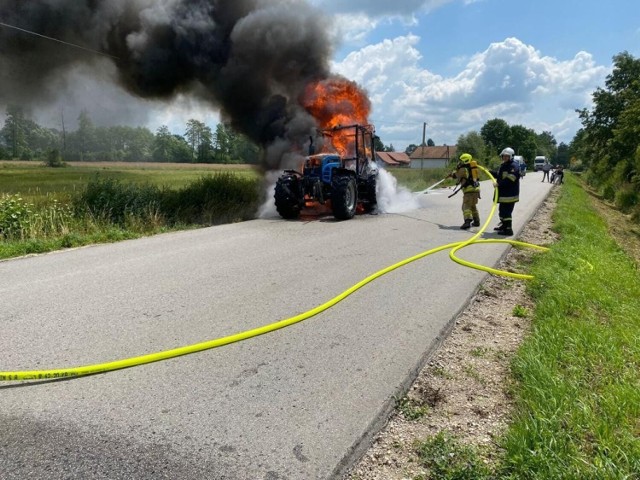 Akcja gaśnicza na drodze w Zabrniu koło Szczucina. Strażacy gasili ciągnik z kosiarką. Pojazd był cały objęty płomieniami