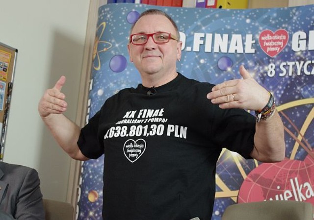 Jerzy Owsiak pokazuje na koszulce zebraną sumę