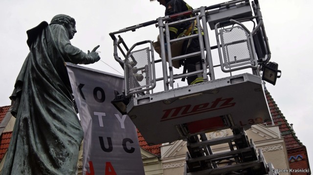 Działacze Komitetu Obrony Demokracji zawiesili dziś (15 sierpnia) na pomniku Kopernika w Toruniu transparent z napisem "KONSTYTUCJA". 

Podobne akcje zorganizowane były w ostatnim czasie w innych polskich miastach, w ich najbardziej rozpoznawalnych miejscach. KOD chce w ten sposób zwrócić uwagę na próby łamania konstytucji w Polsce. 

Po kilkudziesięciu minutach transparent zdjęła wezwana na miejsce straż pożarna.