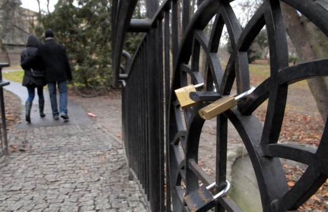 Na balustradzie kładki nad oczkiem wodnym wisi kilkanaście kłódek zakochanych