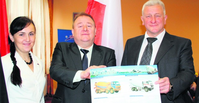 Prezes Linter Group Leszek Łazarczyk (w środku) ze zdjęciami ciężarówek, jakie będzie produkowała jego fabryka