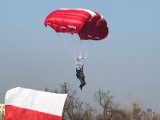 Policjant w roli spadochroniarza z biało-czerwoną flagą nad Gnieznem