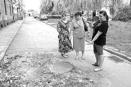 Katarzyna Dalak, Wiesława Bąk i Gabriela Jazek pokazują przysypaną dziurę w jezdni.