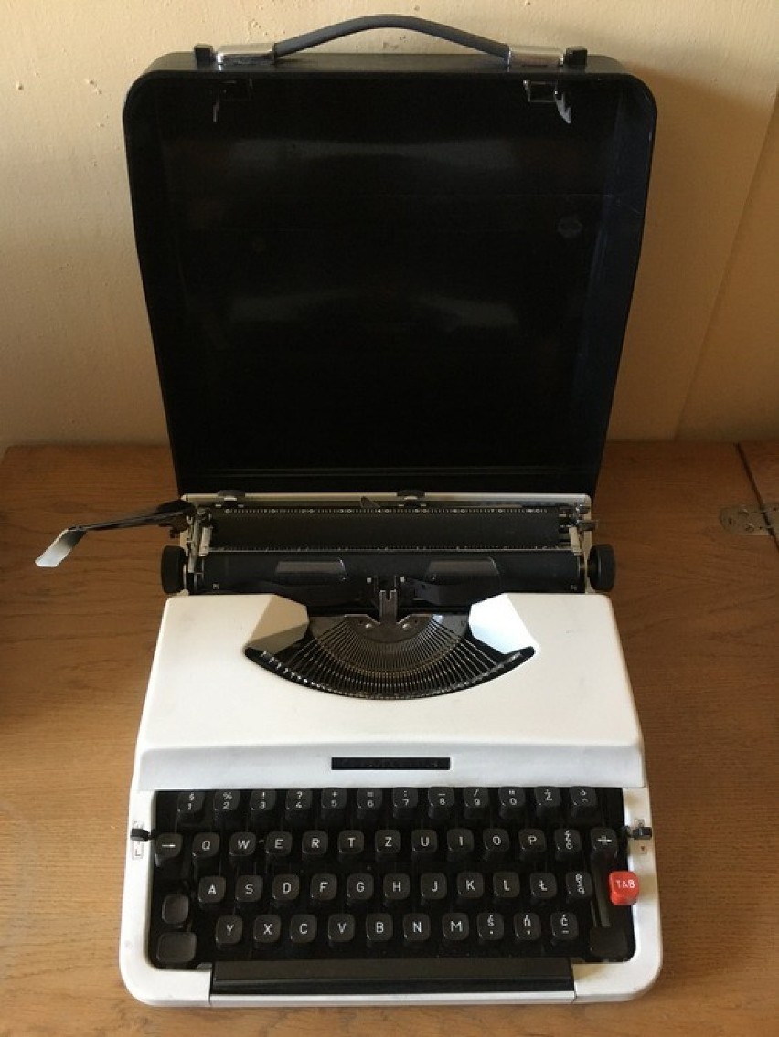 Klasyczna, walizkowa maszyna do pisania z białą obudową....