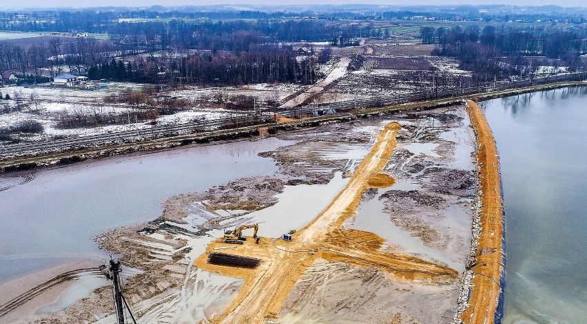 Nad stawem, drogą powiatową i torami pobiegnie prawie...