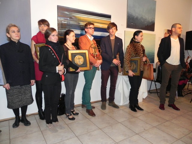 Rodzinna fotografia uczestników 11 Jesiennego Salonu Sztuki w Ostrowcu Świętokrzyskim na tle pracy nagrodzonej Grand Prix.