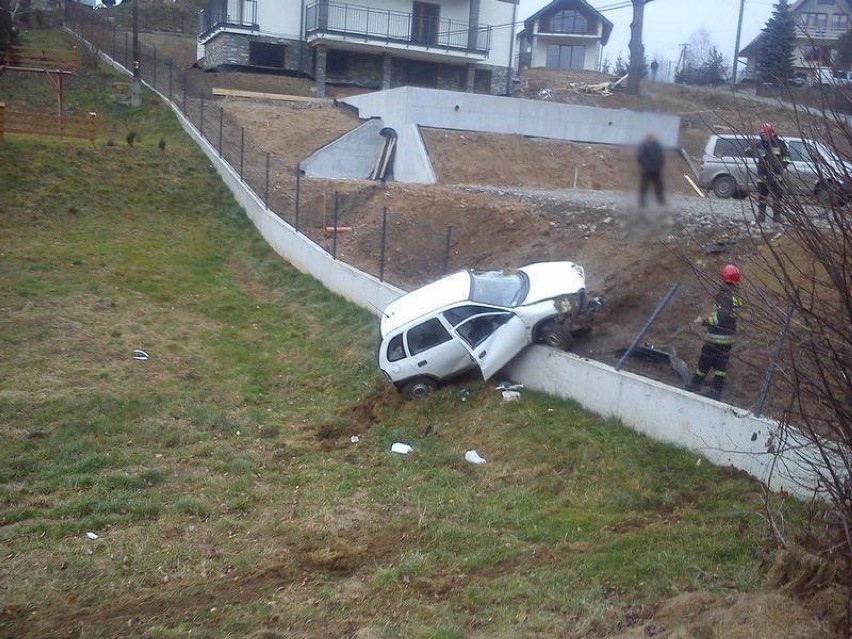 Wóz osobowy przetoczył się przez dach i zawisł na ogrodzeniu